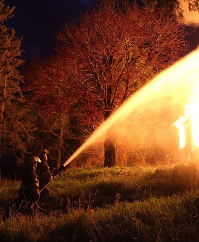  Two firefighters spraying burning house with fire hose