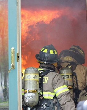  Two firefighters spraying house burn with fire hose